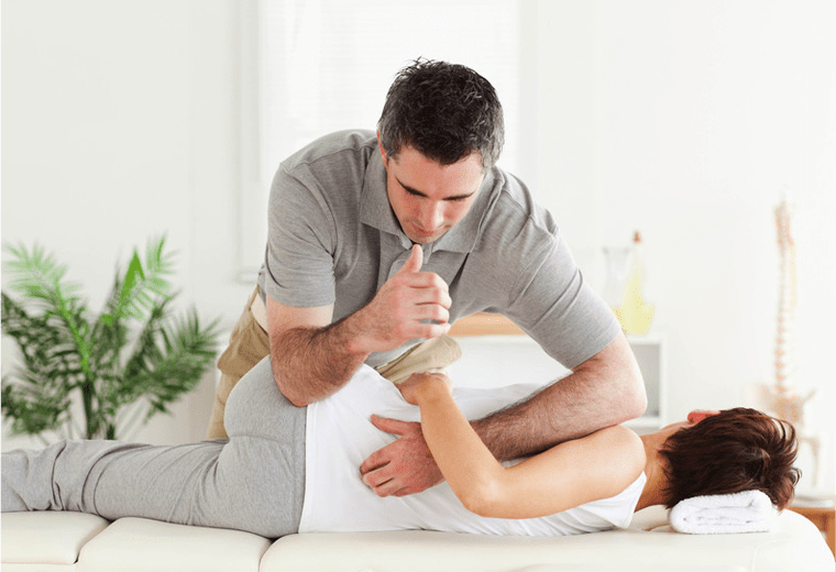 A Chiropractor is performing a massage on a woman's back.